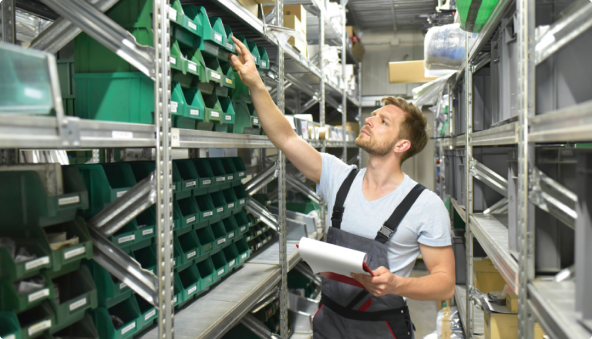 Male in apron in a stock room reaching up to check a green container